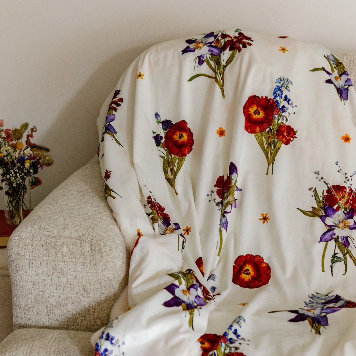 Throw blanket with floral bouquet design on a beige couch