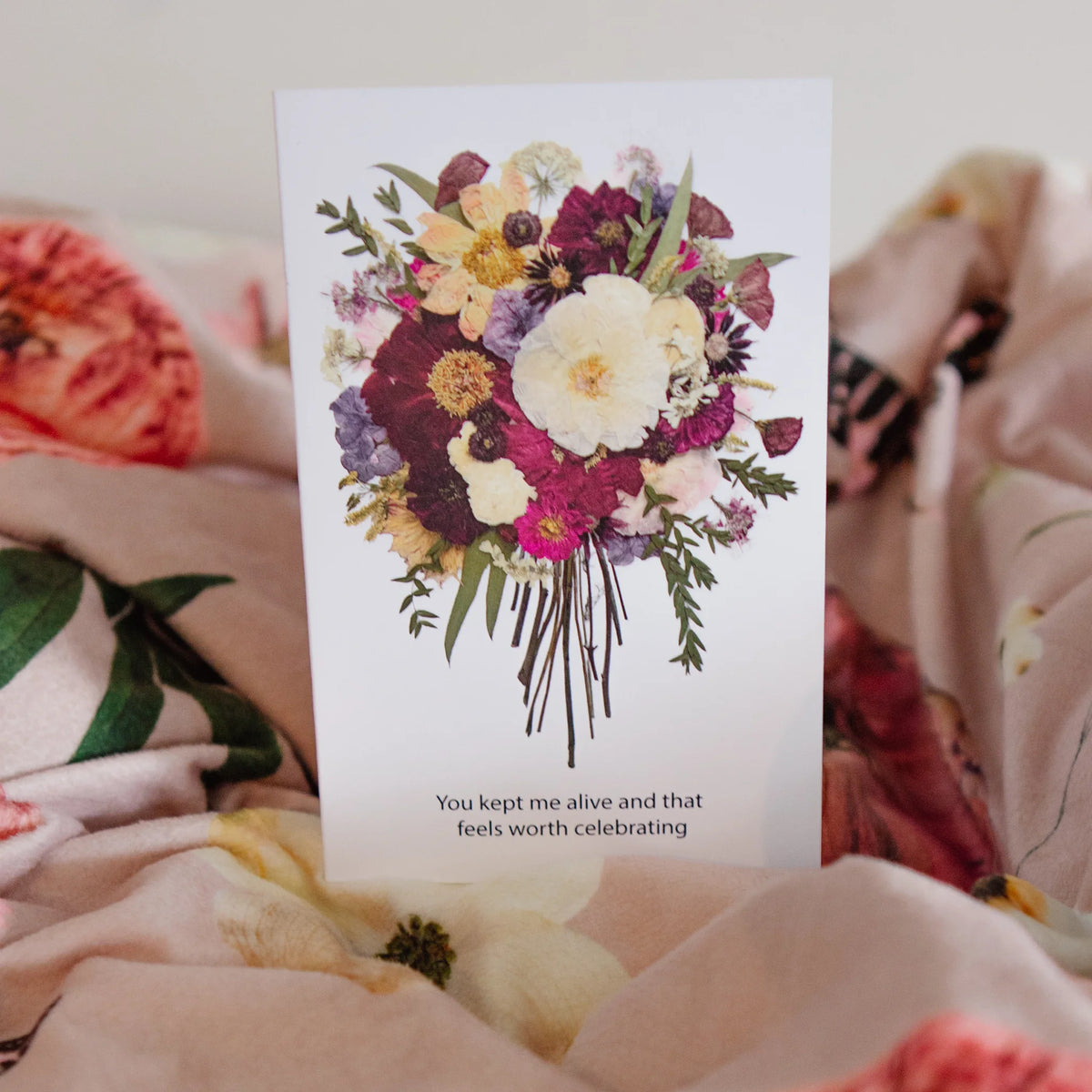 Floral card with a bouquet of flowers and text on a floral throw blanket