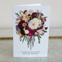Greeting card with a colorful floral design and text on a textured surface.