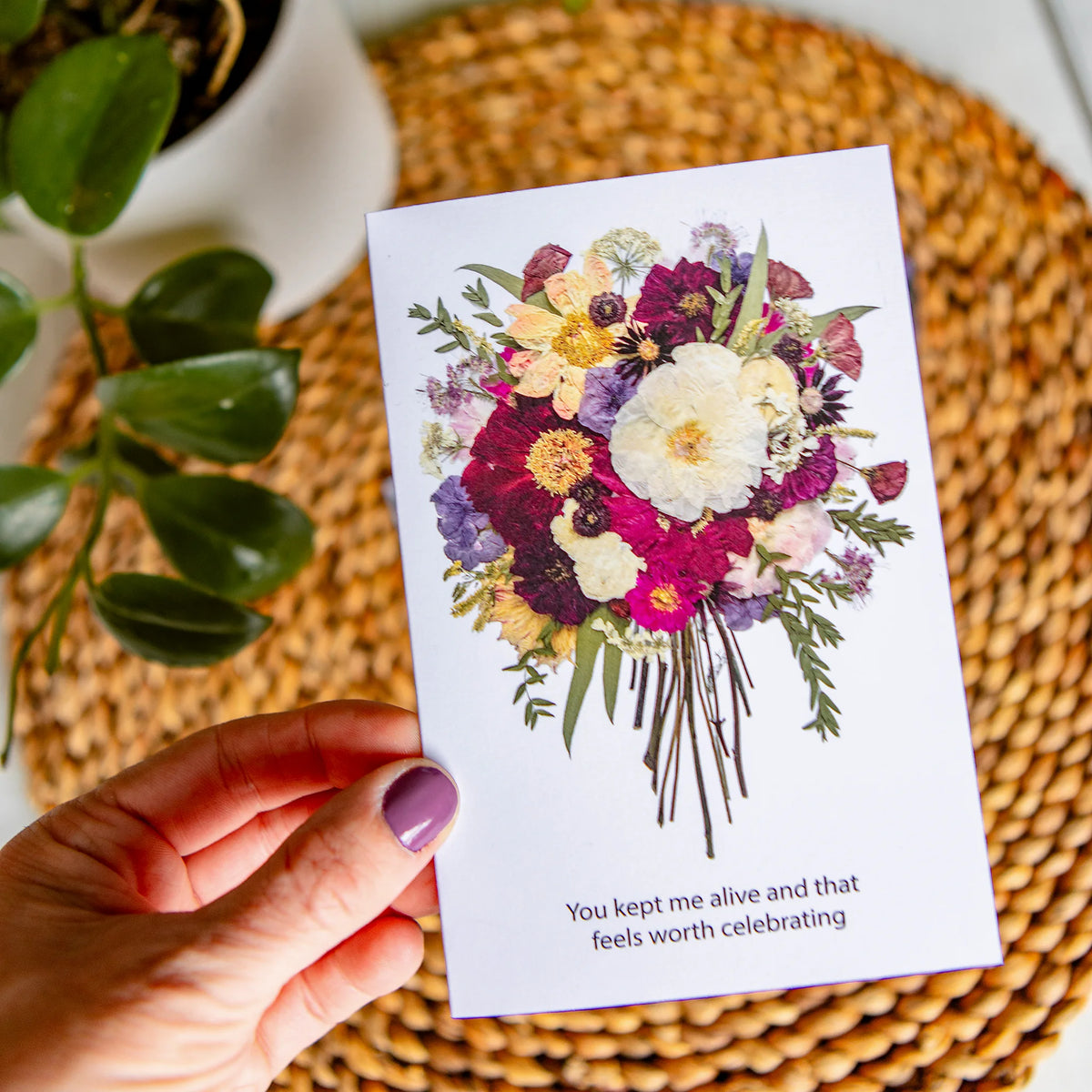 Hand holding a card with a floral design and text on a woven surface.