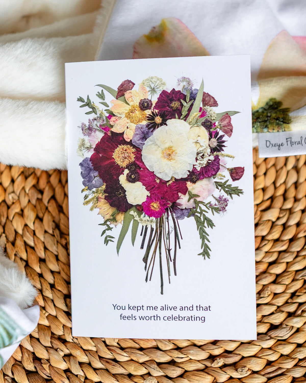 Floral card with a bouquet of flowers and text on a woven surface