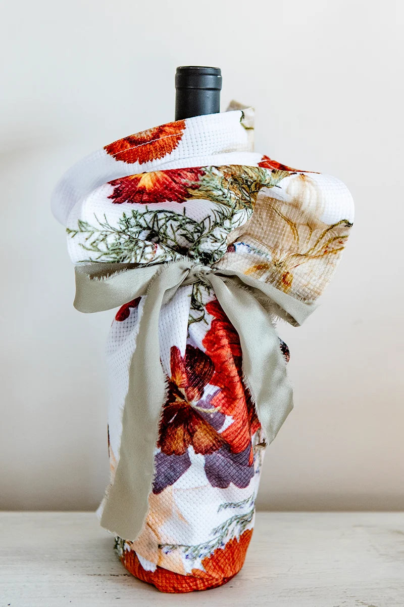 Floral tea towel wrapped around a wine bottle and tied with a sage ribbon as a hostess gift