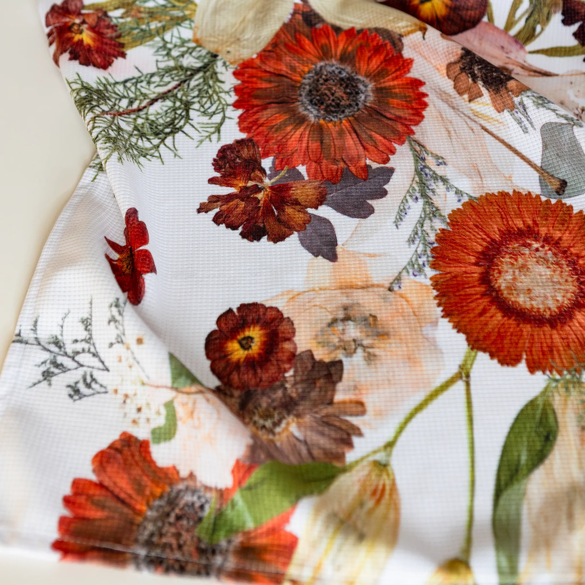 Close-up of a floral tea towel with autumnal colors on a white background