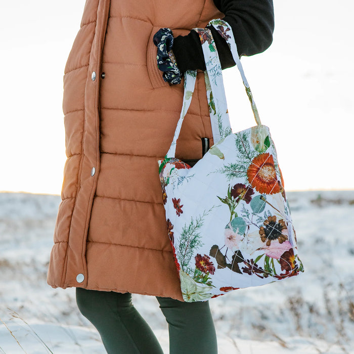 Person wearing a floral tote bag with a snowy background