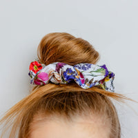 Floral scrunchie on a bun against a plain background
