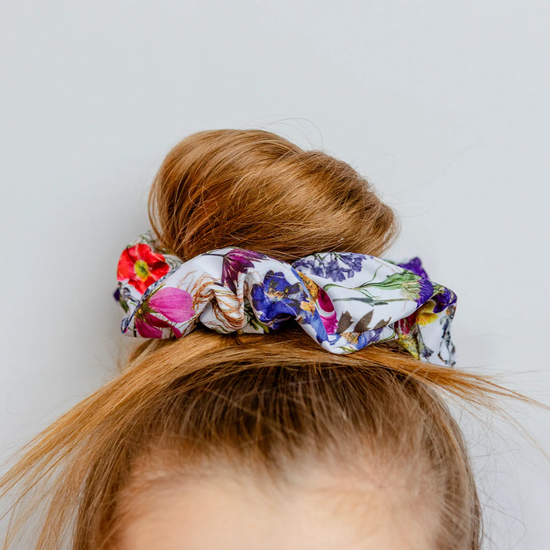 Floral scrunchie on a bun against a plain background