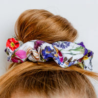 Colorful floral scrunchie on a bun against a white background