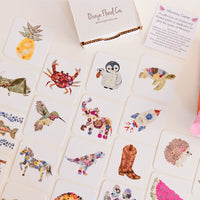 Memory game with floral and nature-themed cards on a white surface, featuring Oxeye Floral Co. branding.