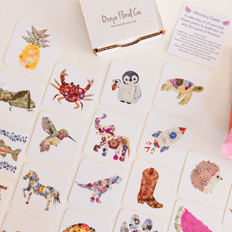 Memory game with floral and nature-themed cards on a white surface, featuring Oxeye Floral Co. branding.