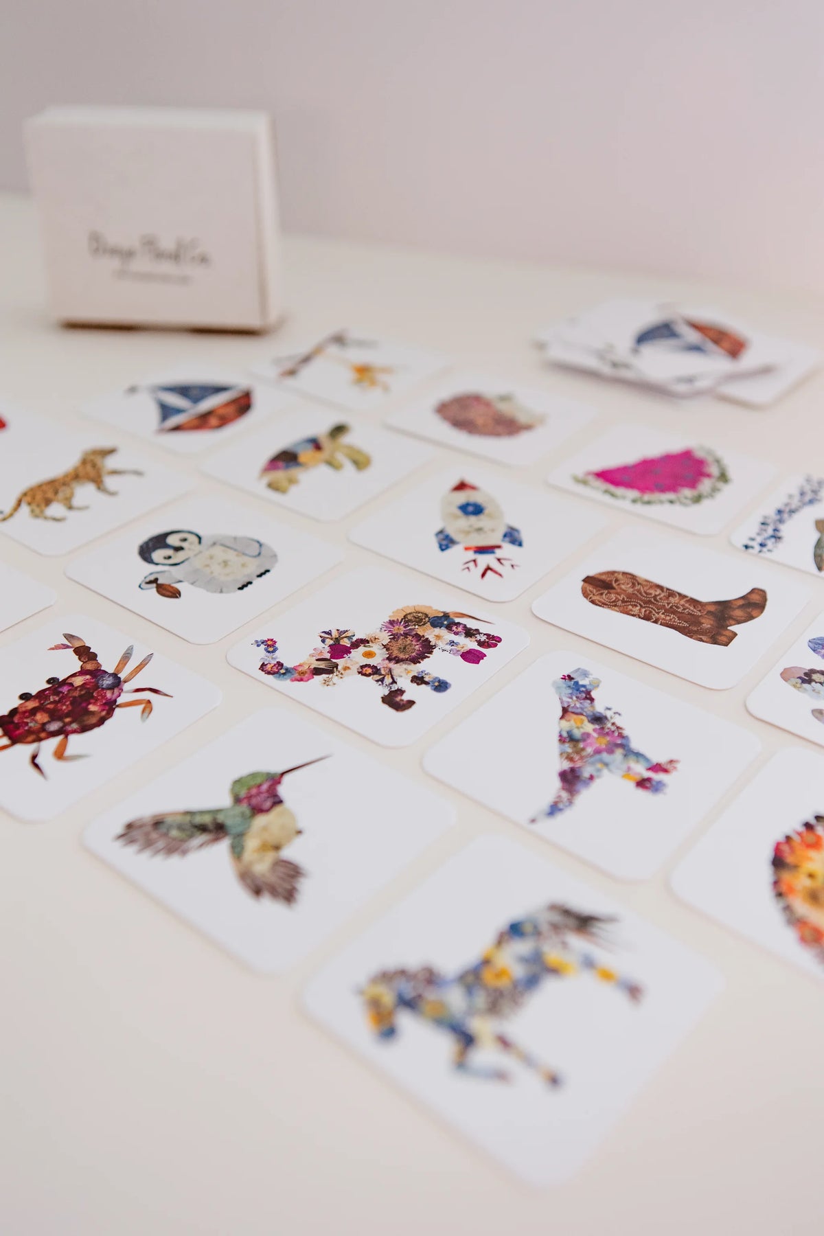 Collection of colorful memory game cards on a light surface with a small box in the background.