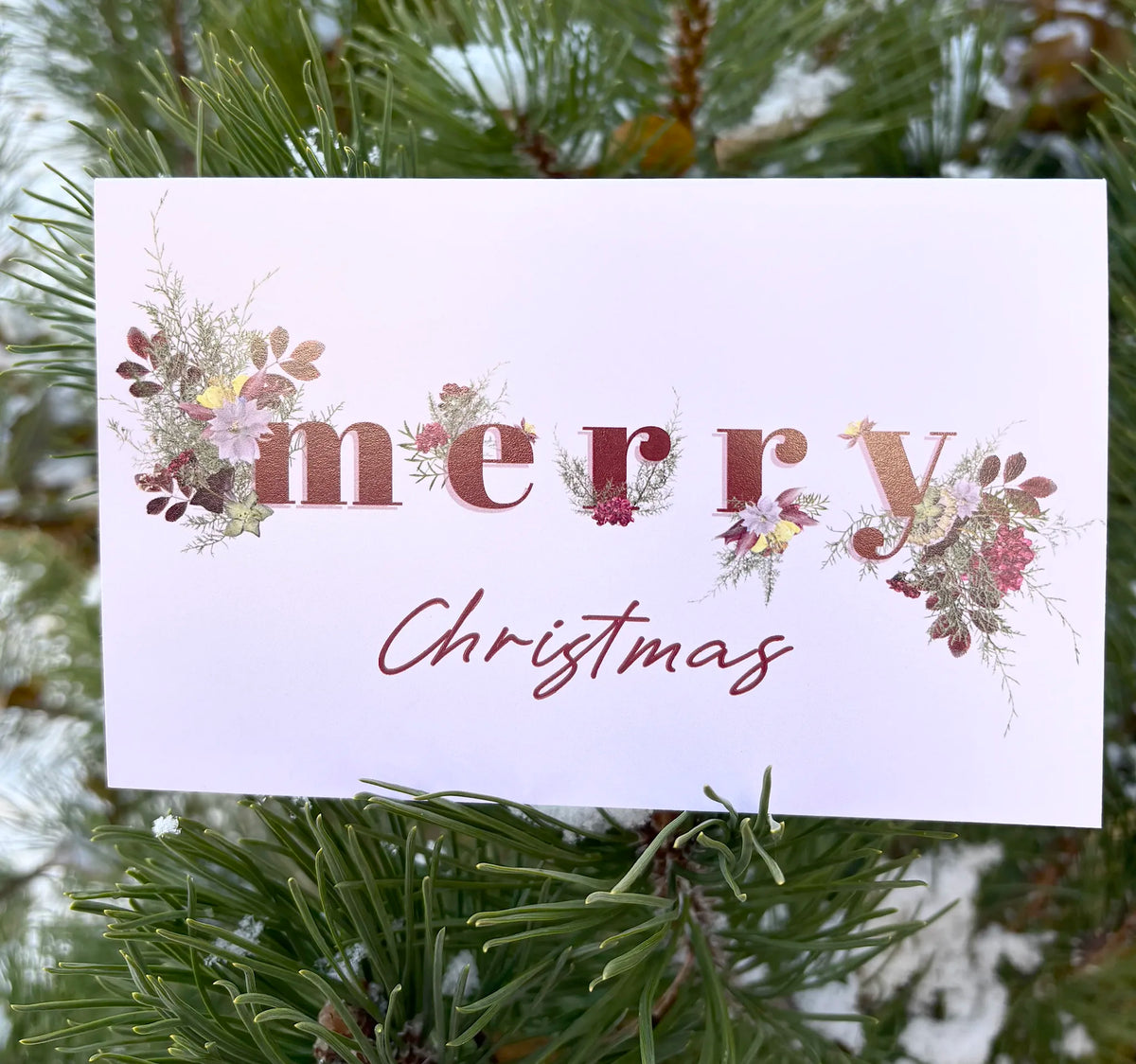 light pink christmas card with the words "merry christmas" and flowers