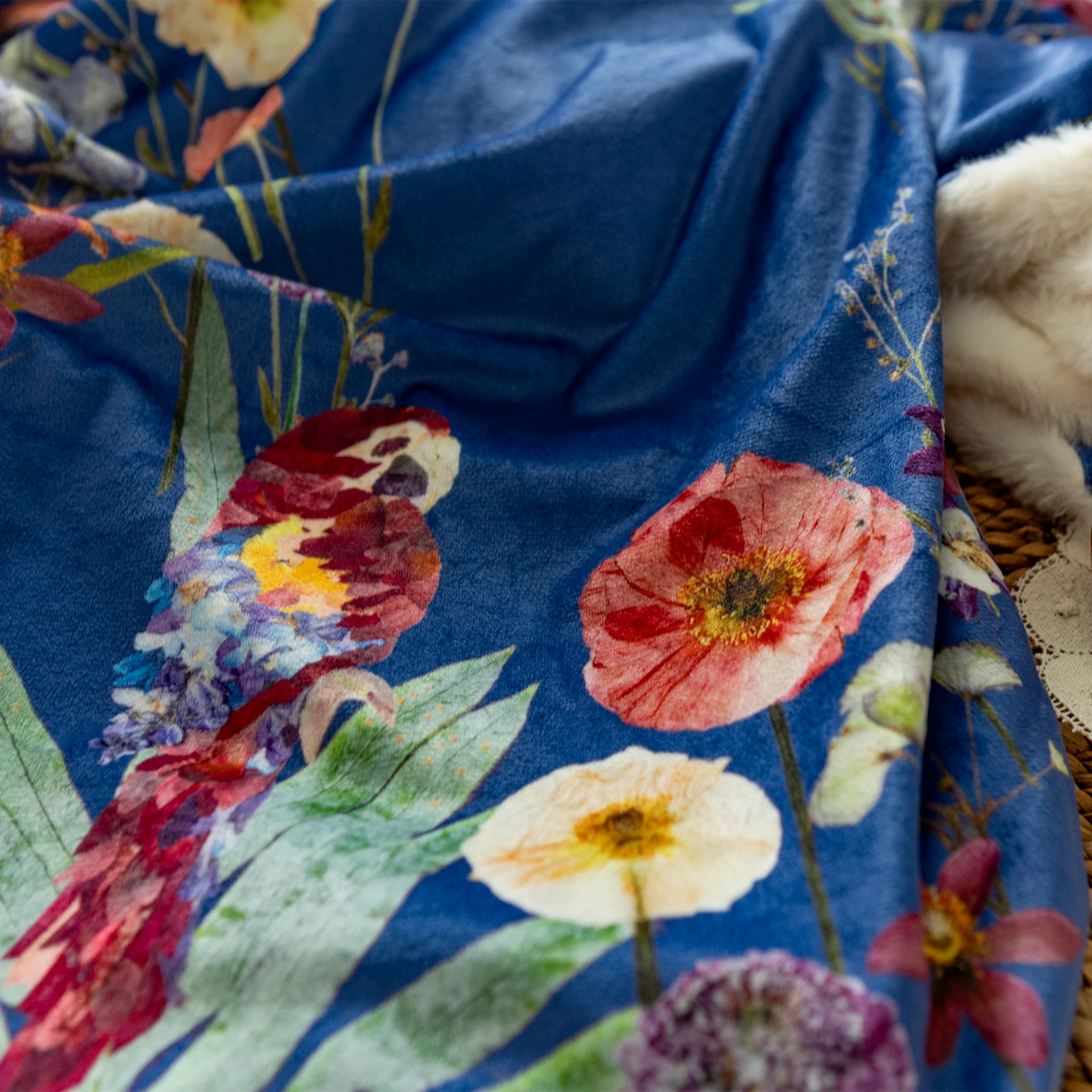 Closeup of pressed flower parrot and florals printed on a blue throw blanket with fluffy minky fabric backing