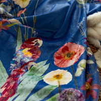 Closeup of pressed flower parrot and florals printed on a blue throw blanket with fluffy minky fabric backing