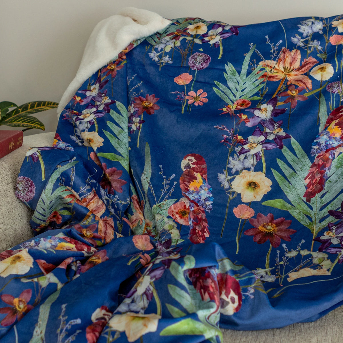 Blue throw blanket with tropical floral and parrots design on a couch