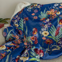 Blue throw blanket with tropical floral and parrots design on a couch