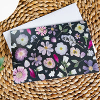 Pressed flower greeting card on a woven surface