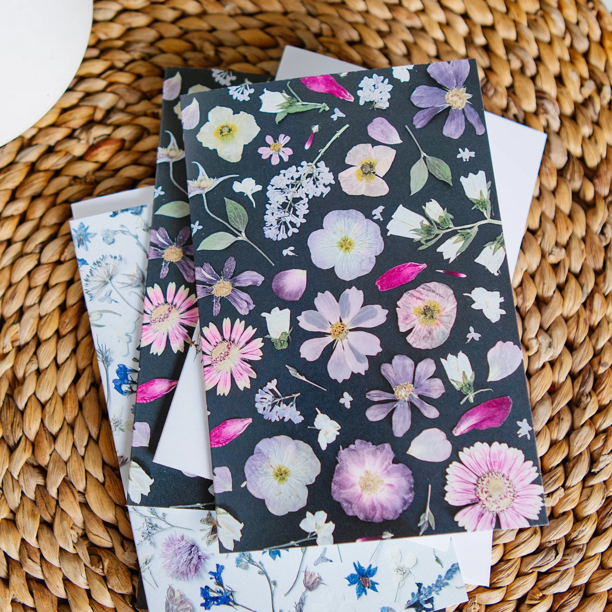 Greeting cards with pressed flower designs on a woven surface