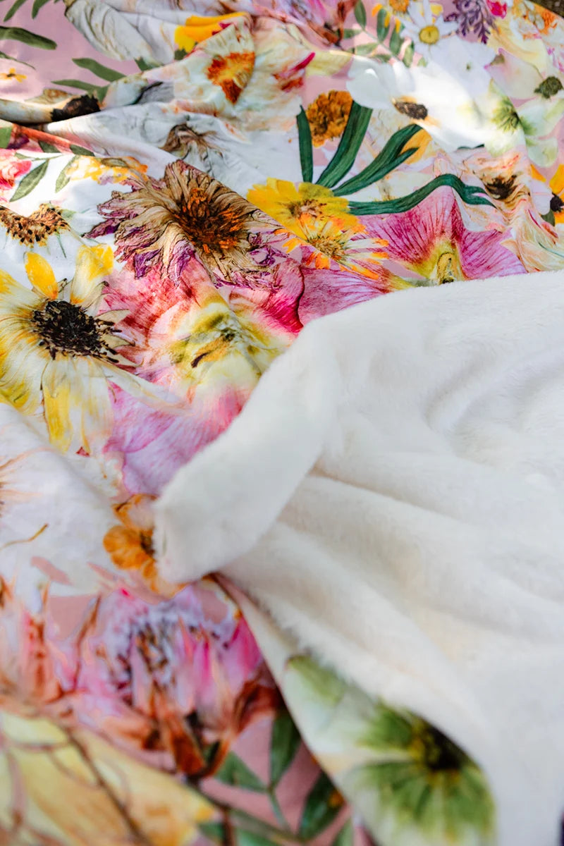 Close-up of a pink floral throw blanket with soft white plush backing