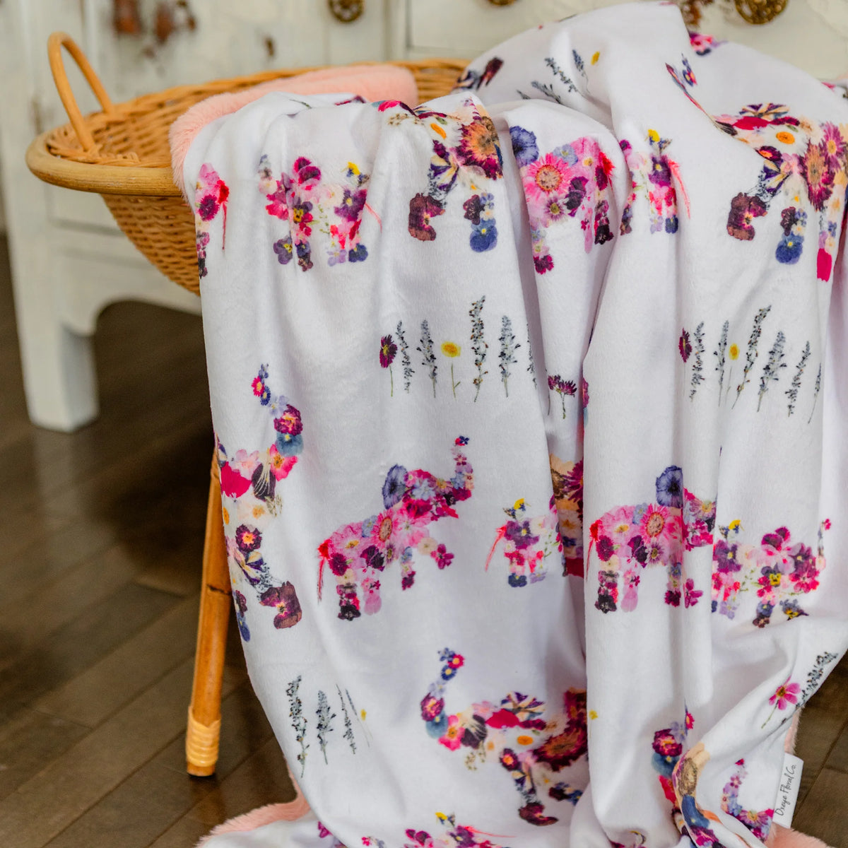 Floral and elephant-patterned fabric draped over a chair with a wooden floor background