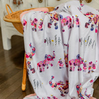 Floral and elephant-patterned fabric draped over a chair with a wooden floor background