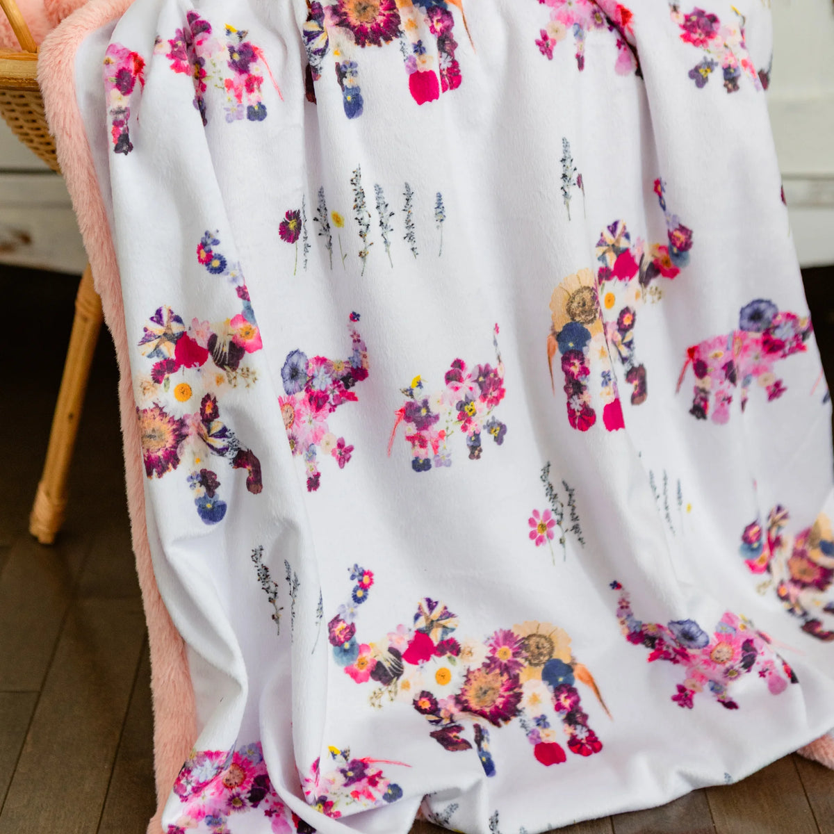 Floral-patterned blanket with colorful animals on a wooden floor.