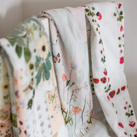 Floral-patterned swaddling blankets hanging against a neutral background