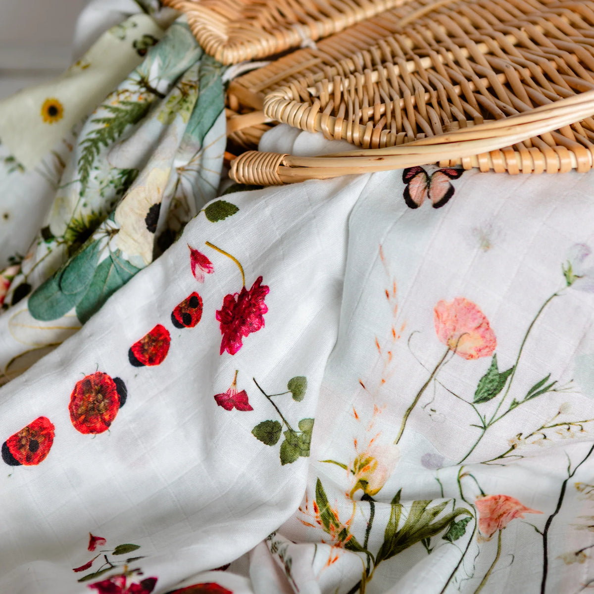 Floral-patterned muslin blankets with a wicker basket in the background
