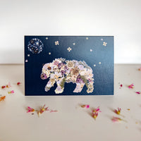 pressed floral bear walking under a flower night sky on a greeting card