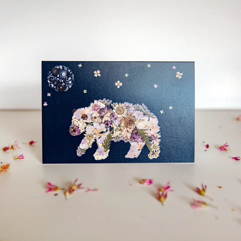 pressed floral bear walking under a flower night sky on a greeting card
