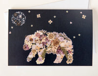 Holiday card artwork showing a pressed flower bear and night sky