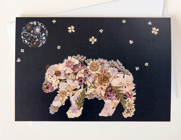 Holiday card artwork showing a pressed flower bear and night sky