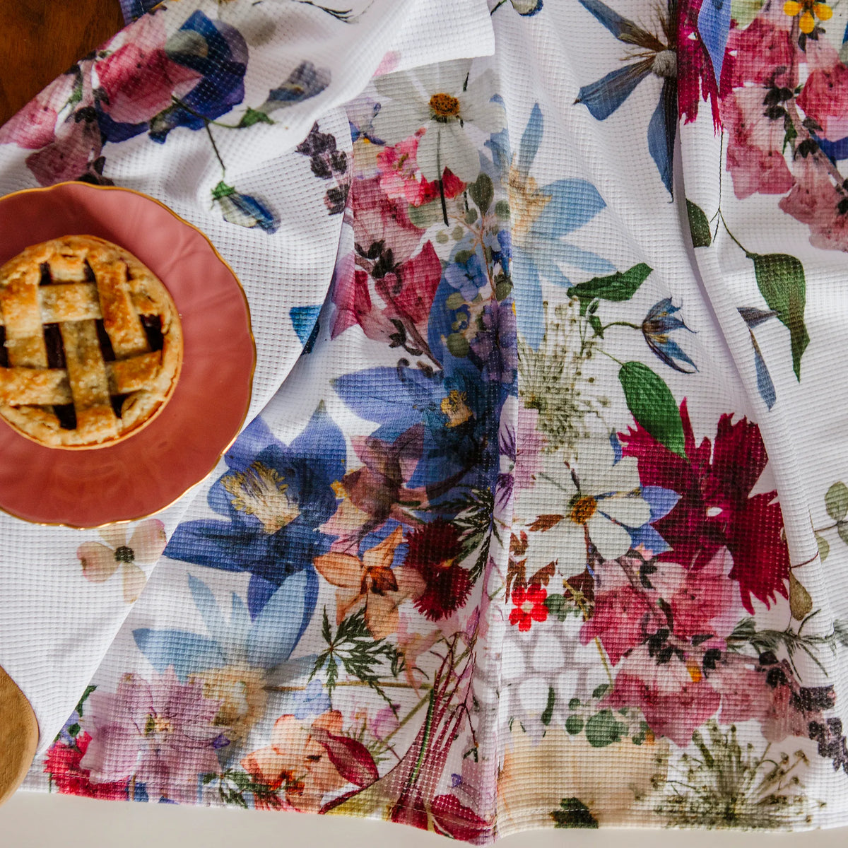 Floral-patterned tea towel with a pie on a red plate