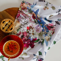 Decorative pressed flower tea towel with a pie and teacup on a wooden surface