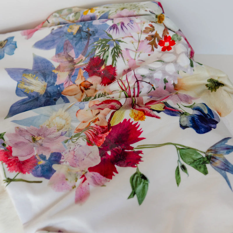 Floral-patterned blanket with colorful pressed flowers on a white background