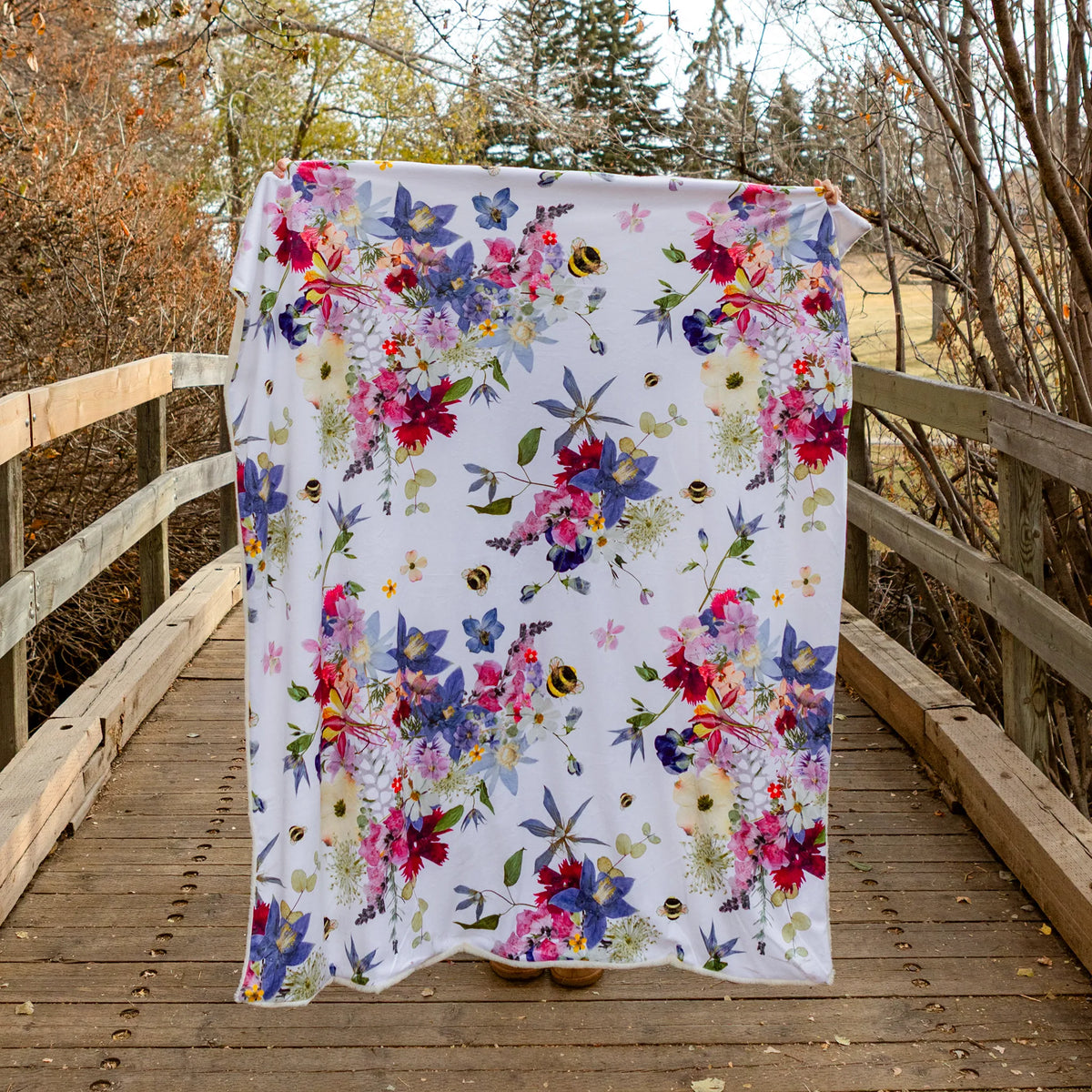 Floral blanket draped over a wooden bridge with trees in the background