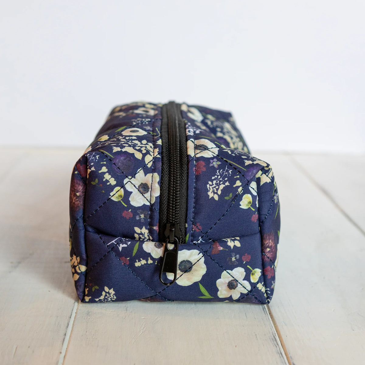 Floral-patterned cosmetic bag on a light wooden surface