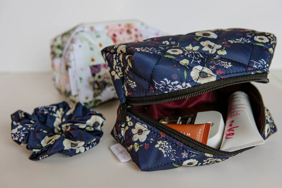 Floral-patterned makeup bag with toiletries and a scrunchie on a light surface