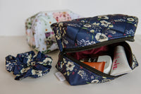 Floral-patterned makeup bag with toiletries and a scrunchie on a light surface