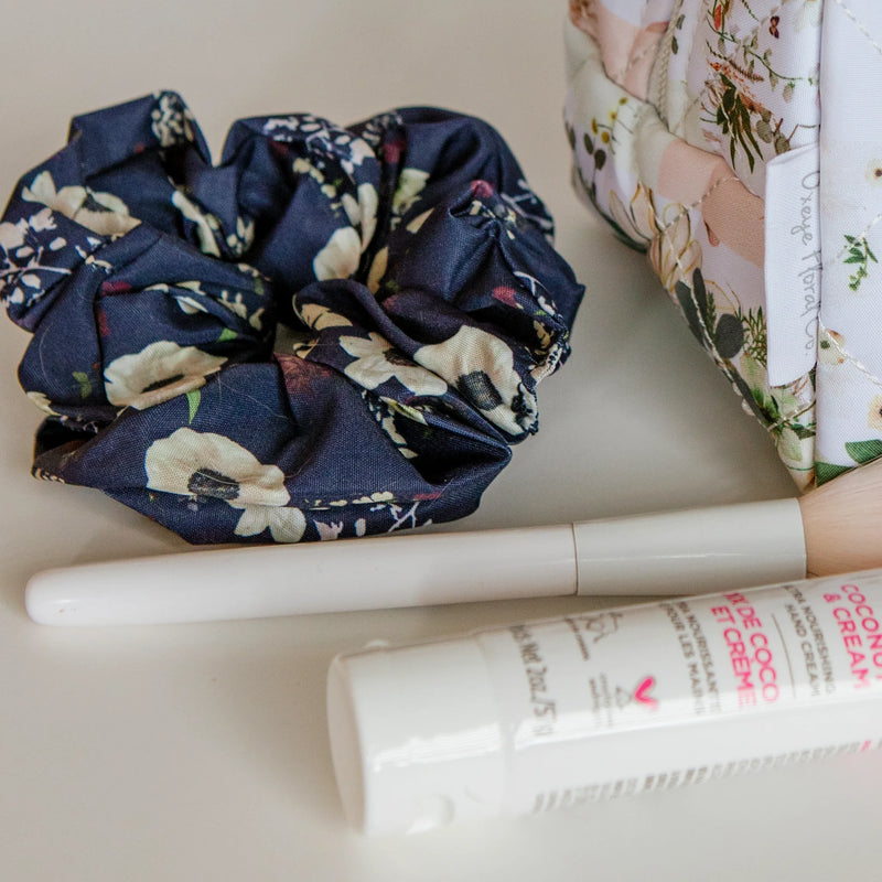 Floral scrunchie and skincare products on a white surface