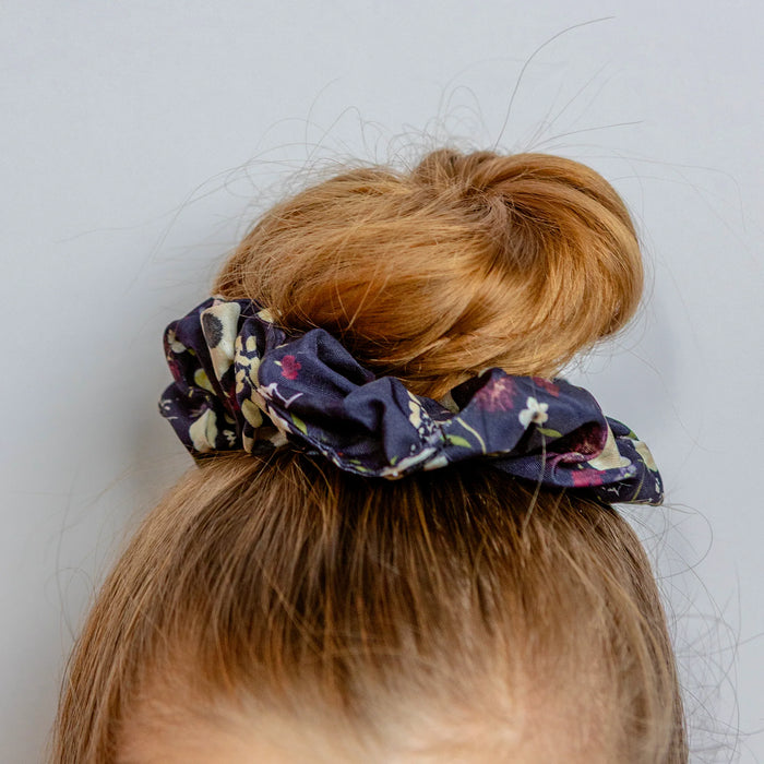 Floral scrunchie on a bun against a plain background