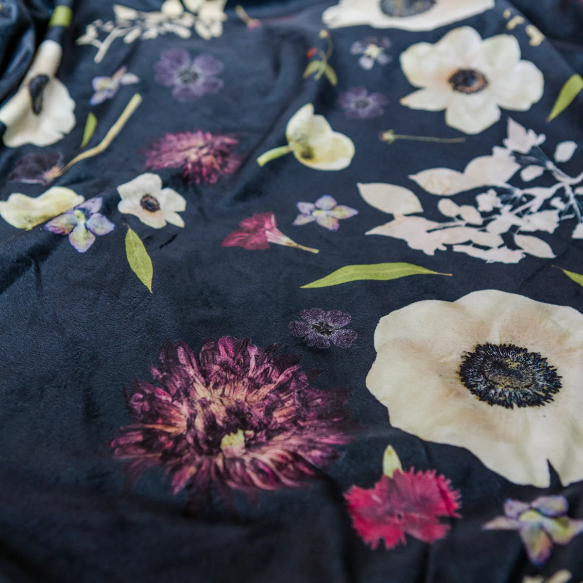 Pressed floral throw blanket with various flowers on a dark background