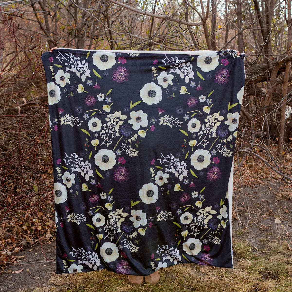 Floral-patterned blanket draped over a person in a forest setting