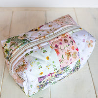 Floral-patterned quilt design bag on a light wooden surface
