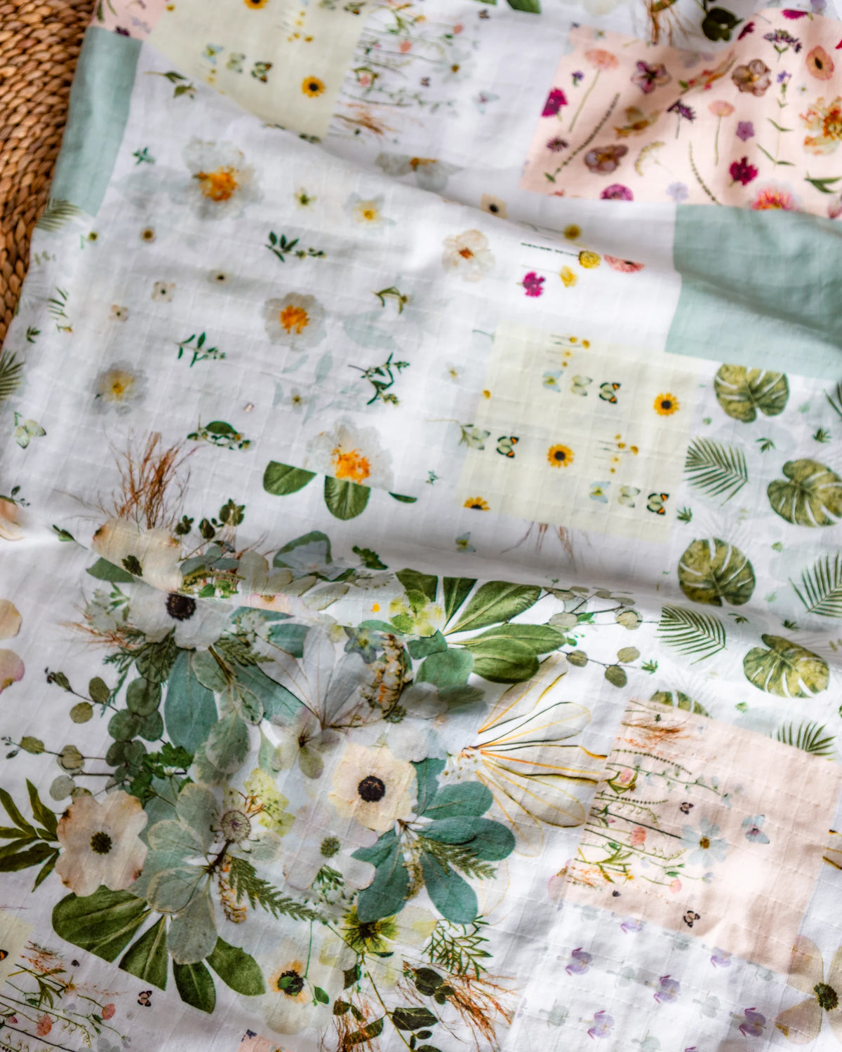 Patchwork style floral baby swaddle on a woven background