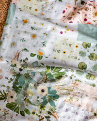Patchwork style floral baby swaddle on a woven background