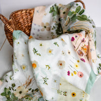 Floral muslin baby swaddle in a wicker basket on a light background