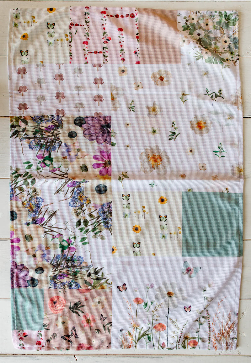 Patchwork quilt style tea towel with floral and butterfly patterns on a wooden surface