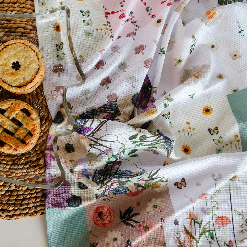 Floral and checkered tea towel with a woven basket and pies in the background