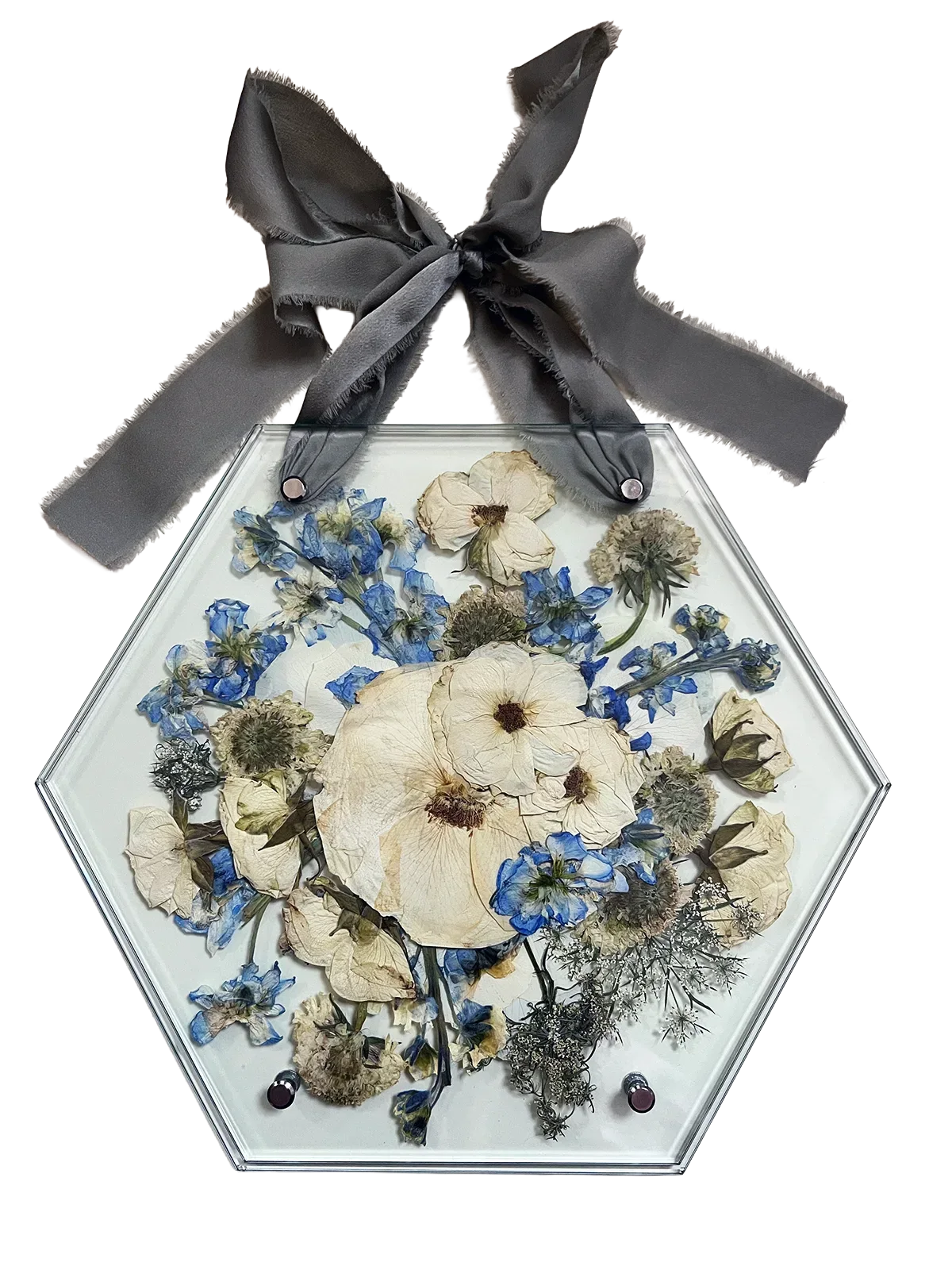 Hexagonal glass frame with pressed flowers and a gray ribbon on a white background