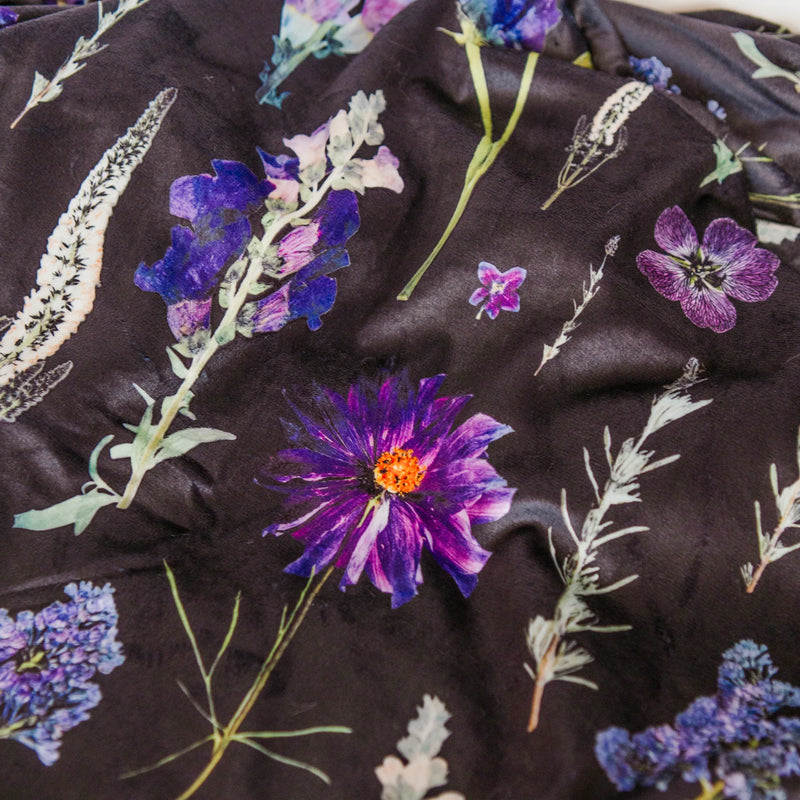 Floral patterned blanket with purple and blue flowers on a dark background